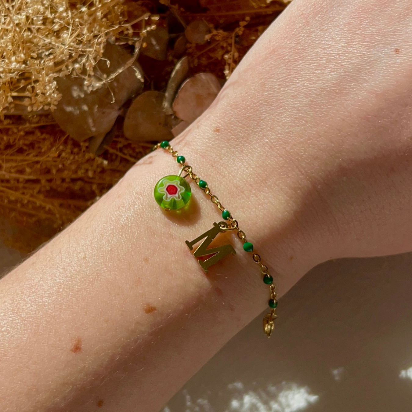 bracelet maddy personnalisable avec lettre et perle Millefiori, présenté ici avec la lettre M et perle verte
