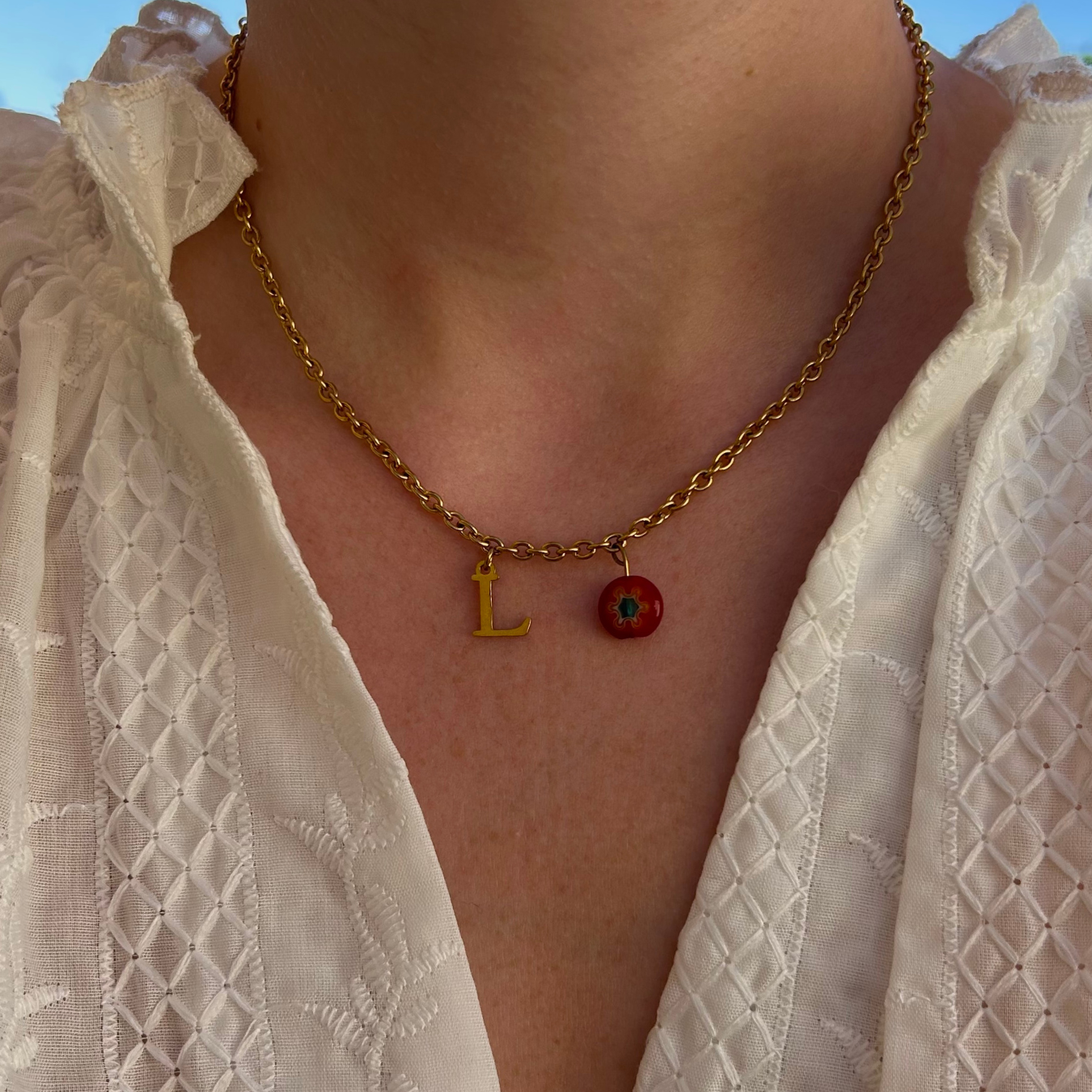 collier flavie personnalisable avec lettre et perle Millefiori, présenté ici avec la lettre L et perle rouge