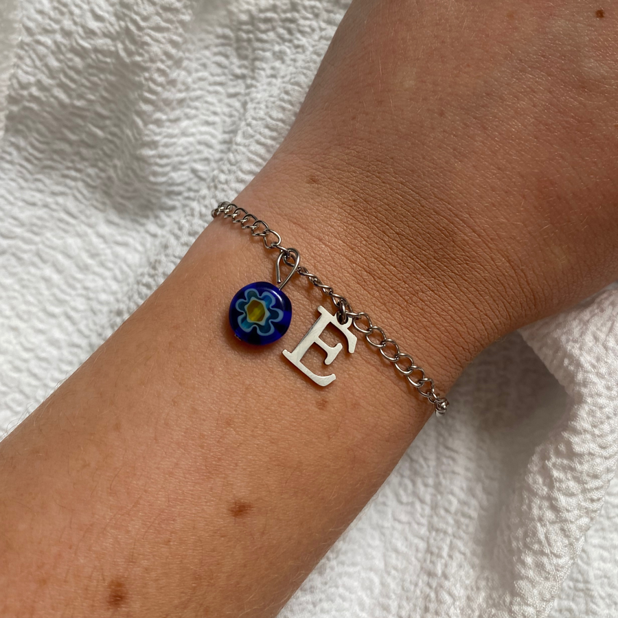 bracelet echo argenté personnalisable avec lettre et perle Millefiori, présenté ici avec la lettre E et perle bleue