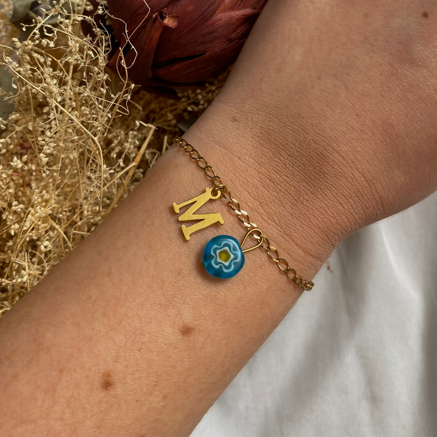 bracelet millie doré personnalisable avec lettre et perle Millefiori, présenté ici avec la lettre M et perle bleue